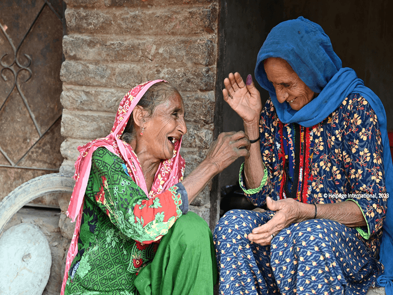 Two older women in colorful clothing laugh together